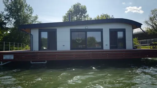 Hausbót o rozmere 15,3 x 13,9m určeného na bývanie a rekreáciu pozostáva z pontónu z oceľovej konštrukcie a z nadstavby o rozmere 11,39 x 9,17m. Vonkajšie obloženie pozostáva zo sendvičových PUR panelov.