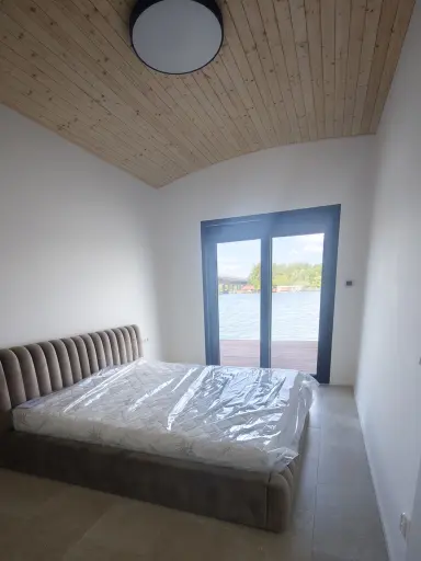 Hausbót o rozmere 15,3 x 13,9m určeného na bývanie a rekreáciu pozostáva z pontónu z oceľovej konštrukcie a z nadstavby o rozmere 11,39 x 9,17m. Vonkajšie obloženie pozostáva zo sendvičových PUR panelov.