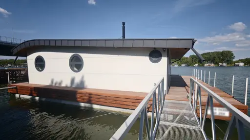 Hausbót o rozmere 15,3 x 13,9m určeného na bývanie a rekreáciu pozostáva z pontónu z oceľovej konštrukcie a z nadstavby o rozmere 11,39 x 9,17m. Vonkajšie obloženie pozostáva zo sendvičových PUR panelov.