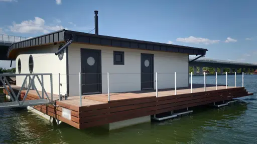 Hausbót o rozmere 15,3 x 13,9m určeného na bývanie a rekreáciu pozostáva z pontónu z oceľovej konštrukcie a z nadstavby o rozmere 11,39 x 9,17m. Vonkajšie obloženie pozostáva zo sendvičových PUR panelov.